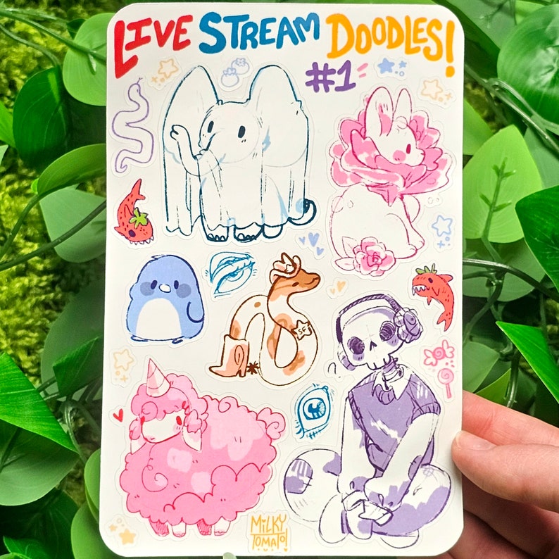 May include: A sheet of stickers with various illustrations, including a ghost, a snake, a penguin, a sheep, a skull, and a rabbit. The stickers are colorful and feature a variety of cartoon characters. The sheet is labeled "Live Stream Doodles! #1".