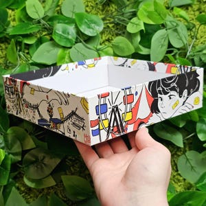 May include: A white rectangular tray with a colourful cartoon design featuring a Ferris wheel, a person with a bandage on their face, and the text "Milk Tokyo".