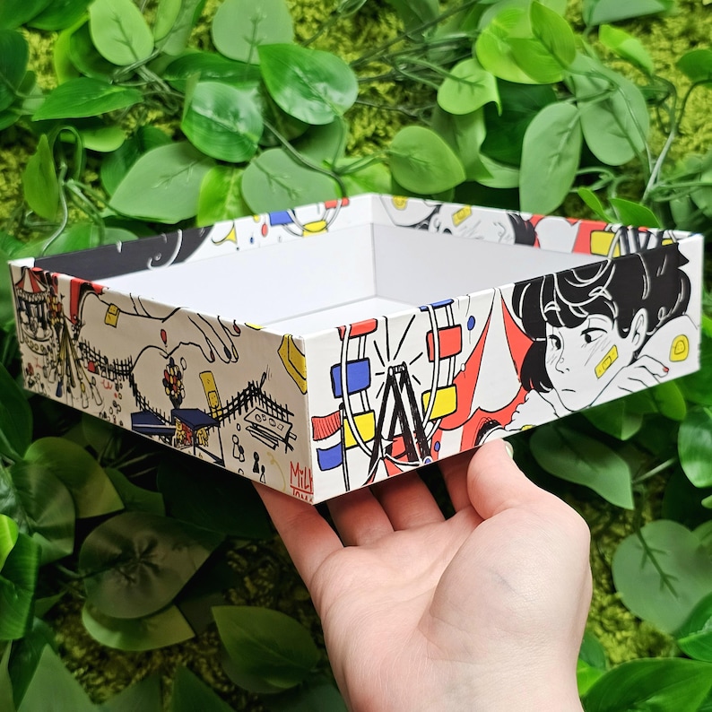 May include: A white rectangular tray with a colourful cartoon design featuring a Ferris wheel, a person with a bandage on their face, and the text "Milk Tokyo".