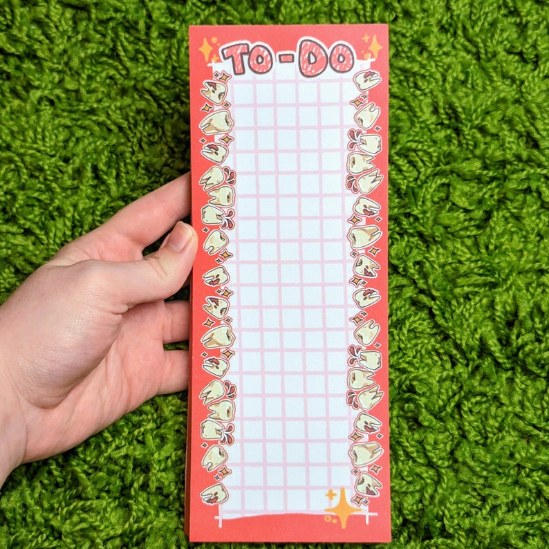 Puede incluir: Bloc de notas rojo para hacer con una cuadr&iacute;cula blanca y un borde de dientes de dibujos animados. El bloc de notas tiene un fondo blanco con una cuadr&iacute;cula rosa y un borde rojo.