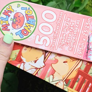 May include: A pink and white jigsaw puzzle box with a cartoon tomato and the words "Milky Tomato!" on the front. The box says "500 Pieces/Pi&egrave;ces/Piezas" and "19.5in x 25.25in".
