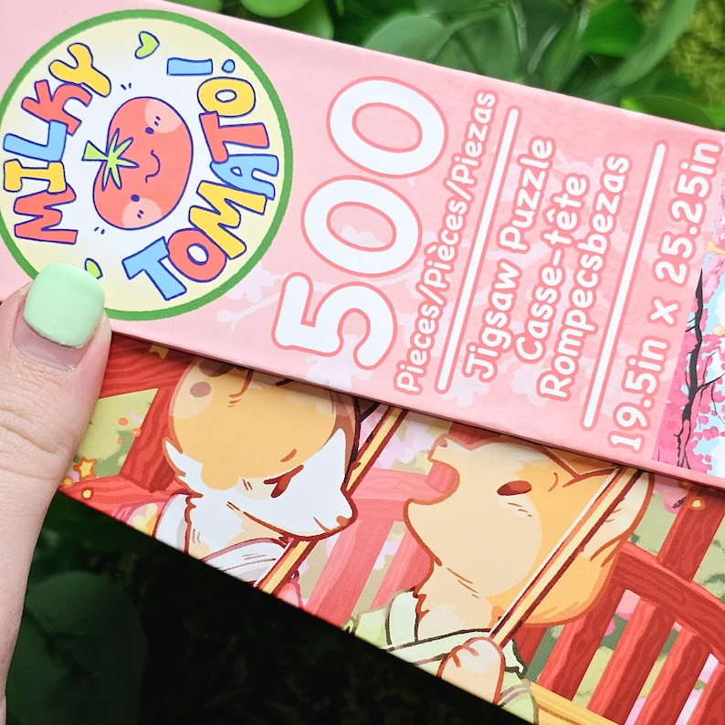 May include: A pink and white jigsaw puzzle box with a cartoon tomato and the words "Milky Tomato!" on the front. The box says "500 Pieces/Pi&egrave;ces/Piezas" and "19.5in x 25.25in".