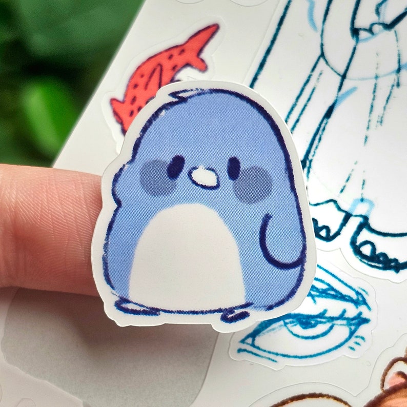 May include: A blue penguin sticker with a white belly and black eyes. The penguin is standing on a white background.