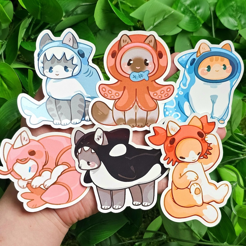 Puede incluir: Seis pegatinas de gato coloridas con diferentes disfraces de animales. Las pegatinas representan un tibur&oacute;n, un pulpo, un cangrejo, una ballena, un camar&oacute;n y un pez. Cada pegatina tiene un lindo gato de dibujos animados que lleva un disfraz de animal diferente.