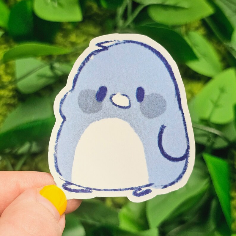 Puede incluir: Una pegatina de ping&uuml;ino azul y blanco con un dise&ntilde;o simple y de dibujos animados. El ping&uuml;ino tiene un peque&ntilde;o pico blanco y ojos negros.