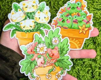 May include: Three sets of stickers featuring cute animal characters in flower pots. The first set features yellow and white cats in a green pot. The second set features green frogs in a brown pot. The third set features pink and white mice in a yellow pot.