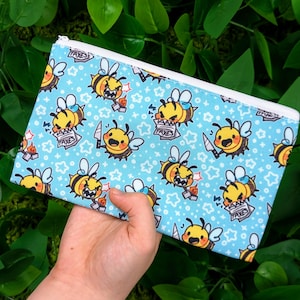 May include: A blue zippered pouch with a repeating pattern of cartoon bees with the text "I AM TAXES" on their shirts.