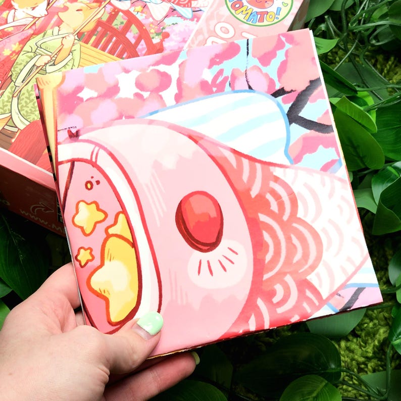 May include: A pink and white book with a cartoon fish design. The fish has a red mouth and yellow stars. The book is closed and has a pink and white floral pattern on the back.
