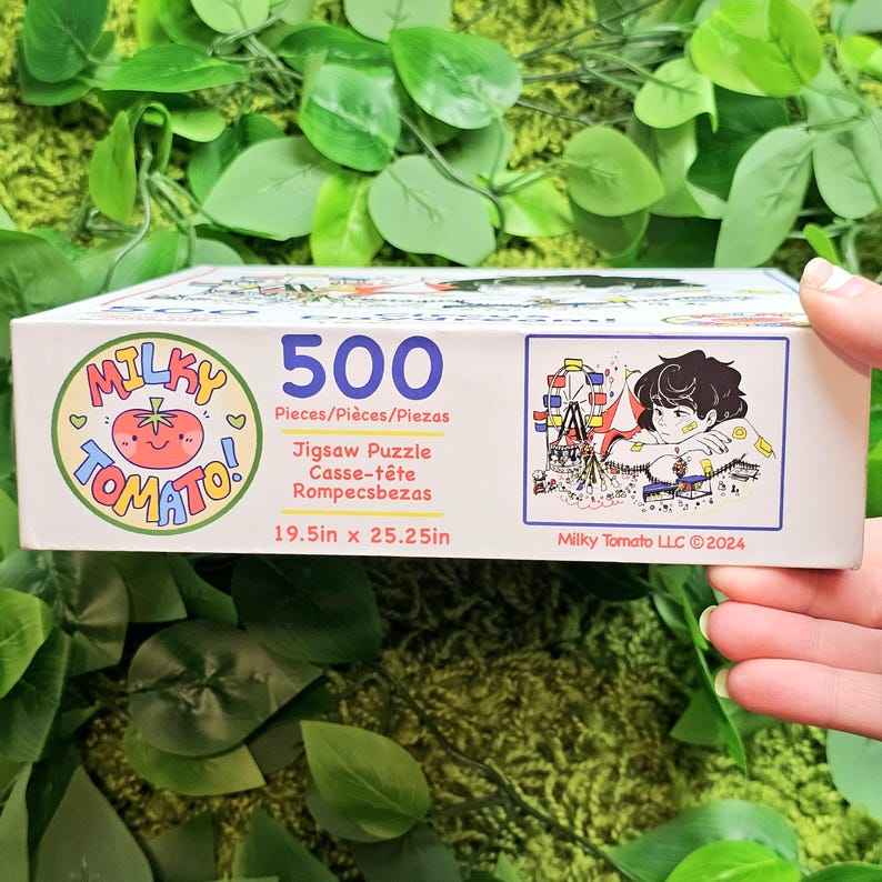May include: A 500-piece jigsaw puzzle box featuring a cartoon tomato illustration and the words "Milky Tomato!" in a pink and white circle. The box also includes a colourful illustration of a Ferris wheel and a person sitting on a bench. The puzzle measures 19.5 inches by 25.25 inches.