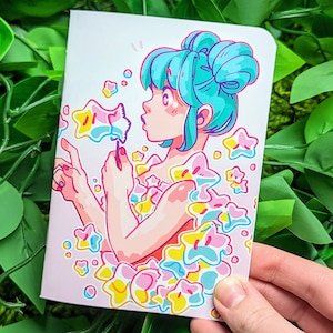 以下が含まれることがあります： 青い髪の人のイラスト。星型の杖でシャボン玉を吹いている。背景はカラフルな星でいっぱいである。