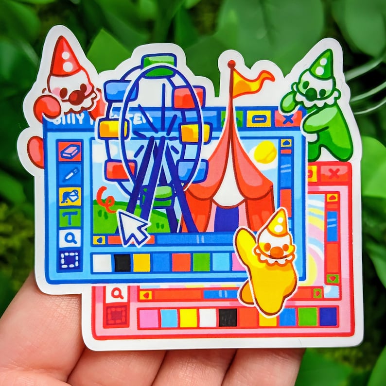 以下が含まれることがあります： コンピューター画面の漫画イラストが描かれたカラフルなステッカー。背景には観覧車とサーカスのテントがあります。画面には、虫眼鏡、筆、テキストツールなどのツールが揃ったツールバーがあります。また、カラーパレットとカーソルも画面に表示されています。ステッカーは、気まぐれで遊び心のあるデザインです。