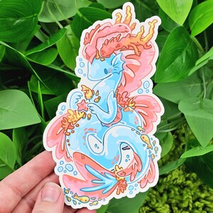 May include: A blue and pink sea dragon sticker with coral and fish details. The sea dragon is holding a starfish in its hand.