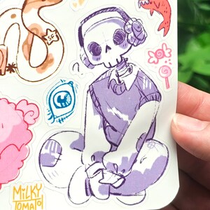 May include: A sticker featuring a cartoon skeleton wearing headphones and a purple sweater. The skeleton is sitting on a cloud with a Milky Tomato logo in the bottom left corner.
