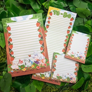 May include: Four different sized notepad designs with a strawberry and leaf border. Each notepad features a different illustration of cartoon ghosts with the text "To-Do" on one of the notepads.