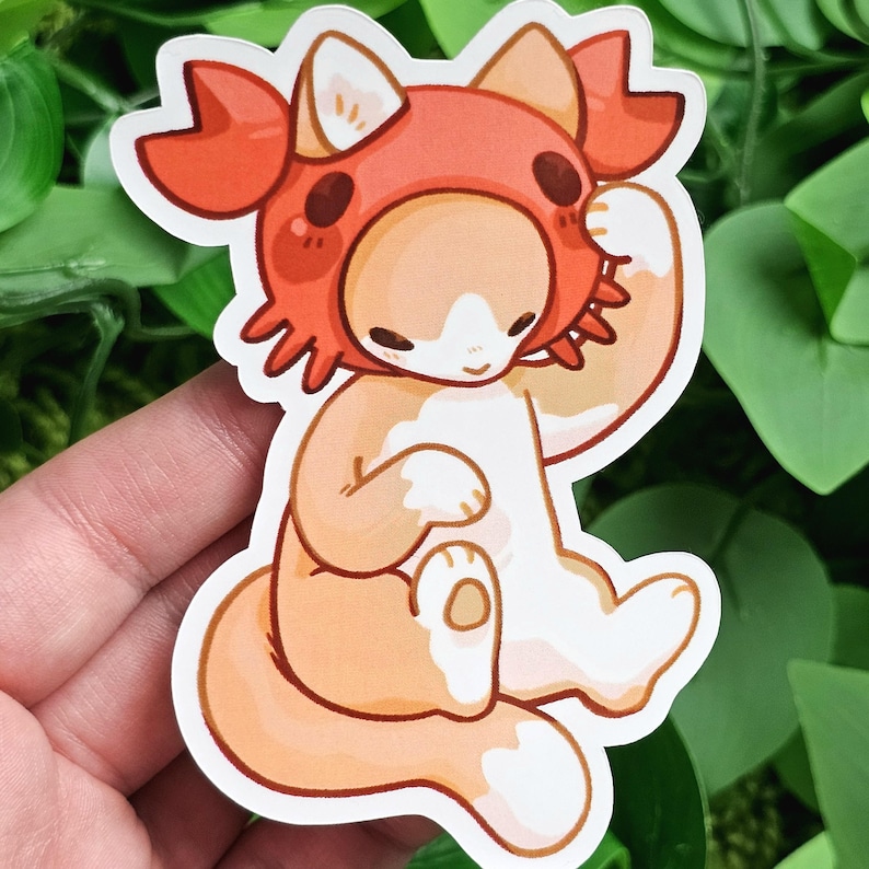 Puede incluir: Una pegatina de un gato de dibujos animados con un disfraz de cangrejo rojo. El gato est&aacute; sentado con las piernas cruzadas y tiene la barriga blanca. La pegatina est&aacute; sobre un fondo verde.