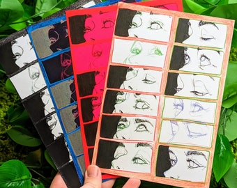 May include: A set of five colorful cards with black and white illustrations of faces. The cards are arranged in a stack, with the top card showing a close-up of a woman's face with her eyes closed. The cards are all different colors, including red, pink, blue, and green.