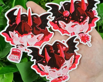 May include: Three stickers featuring a cartoon demon with red horns, bat wings, and a lollipop. One sticker has text that reads "100% REAL BLOOD FLAVOR TYPE A". The stickers are in shades of red, black, and pink.