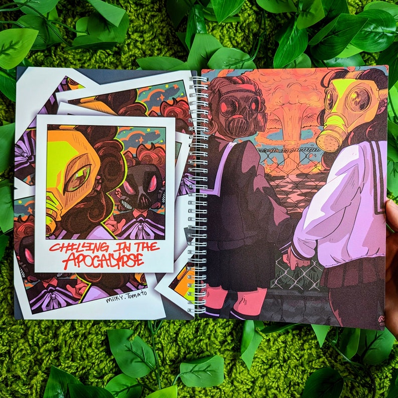 May include: Spiral-bound art journal featuring illustrations of figures in gas masks, set against a post-apocalyptic backdrop. Includes a polaroid-style print with the text "Chilling in the Apocalypse" and the artist's name "milky.tomato".