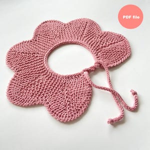 May include: A knitted pink flower-shaped collar with a round neck and tie closure. The collar is made of a soft, textured yarn and has a scalloped edge. The text "PDF file" is in a pink circle.