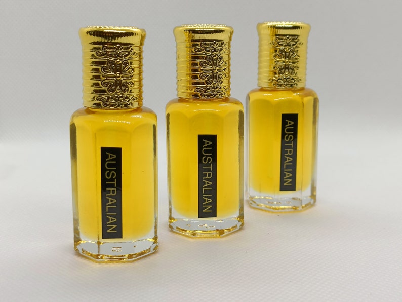 May include: Three perfume bottles with gold-colored caps and clear glass bodies. The bottles are filled with a yellow liquid. Each bottle has a black label that reads "AUSTRALIAN".