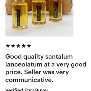 May include: Three small, clear glass bottles with gold-colored caps and labels that read "AUSTRALIAN." The bottles contain a golden liquid and are displayed in front of a wooden background.