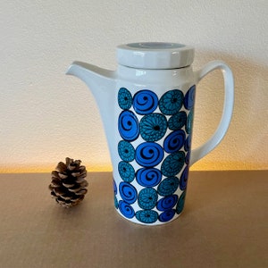 May include: White ceramic coffee pot with a blue and green geometric pattern. The pot has a lid and a handle.