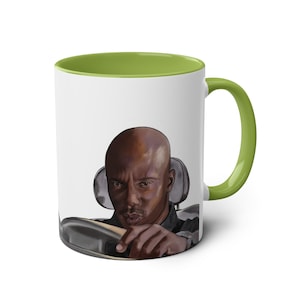Puede incluir: Taza de cerámica blanca con interior y asa verdes. La taza presenta una ilustración detallada de un hombre calvo conduciendo un coche, con una expresión seria. La taza es de tamaño estándar para café o té.