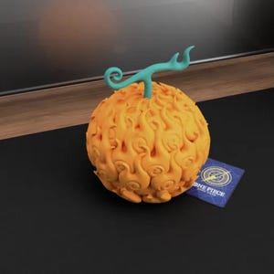 May include: A detailed, orange, flame-like fruit with a teal stem and a small card that says "ONE PIECE CARD GAME". The fruit is the main focus, with a textured surface and a vibrant color. The card is blue with white and gold accents.