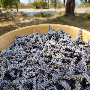 May include: A wooden bowl filled with dried lavender flowers. The flowers are a light purple color and have a delicate fragrance.
