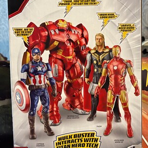 Puede incluir: Figuras de Avengers: Age of Ultron Titan Hero Tech. El embalaje presenta a Capit&aacute;n Am&eacute;rica, Hulkbuster, Thor e Iron Man. Las figuras interact&uacute;an con efectos de luz y frases. El logotipo de Marvel es visible.