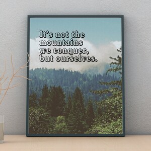 May include: A framed inspirational quote against a backdrop of a misty forest. The quote reads "It's not the mountains we conquer, but ourselves."