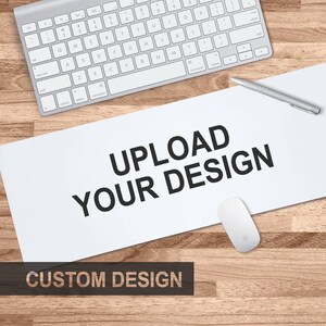 K&ouml;nnte beinhalten: Eine wei&szlig;e Mausmatte mit dem Text "UPLOAD YOUR DESIGN" in Schwarz. Der Text "CUSTOM DESIGN" befindet sich in Schwarz am unteren Rand der Mausmatte.