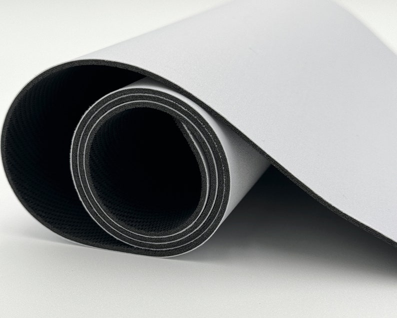 K&ouml;nnte beinhalten: Eine wei&szlig;e und schwarze zusammengerollte Yogamatte. Die Matte ist mit der schwarzen Seite nach au&szlig;en und der wei&szlig;en Seite nach innen zusammengerollt.