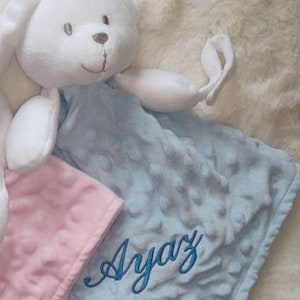 May include: A white plush bear with a light blue and pink baby blanket. The light blue blanket has the name "Ayaz" embroidered in blue script. The blankets have a textured, dotted pattern.