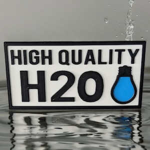 May include: A white rectangular sign with black text that reads "HIGH QUALITY H2O" and a blue water drop icon. The sign is floating in water.