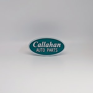 May include: A teal oval sign with white text that reads "Callahan Auto Parts".
