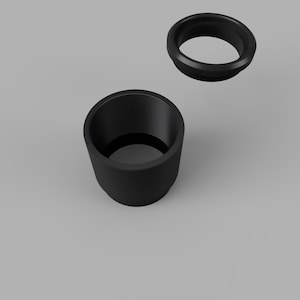 May include: Two black, cylindrical objects. One is a threaded cup, and the other is a ring. The cup has a wide opening and a threaded interior. The ring is a smaller, circular piece with a beveled edge. Both objects are set against a gray background.