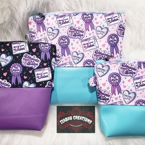 May include: Three different zippered pouches with a purple, blue, and black background. Each pouch has a repeating pattern of hearts, stars, and ribbons with the text "Chronic Spooky Babe" and "Drink Your Water".