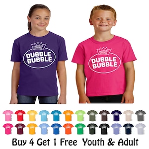 May include: Two children wearing purple and pink t-shirts with the text "Dubble Bubble" in a white oval. The shirts have a crown graphic above the text. Below are various colored t-shirts with the text "Buy 4 Get 1 Free Youth & Adult."