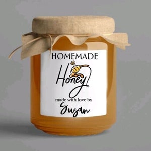 May include: A glass jar filled with honey, with a white label that reads "HOMEMADE Honey made with love by Susan". The label features a cartoon bee with a yellow body and black stripes.