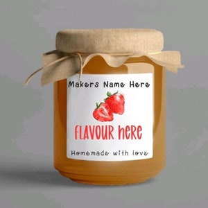 Può includere: Un barattolo di vetro pieno di marmellata d'arancia, sormontato da un coperchio di carta marrone e legato con uno spago. Il barattolo ha un'etichetta bianca con fragole rosse e il testo "Makers Name Here", "FLAVOUR here" e "Homemade with love".