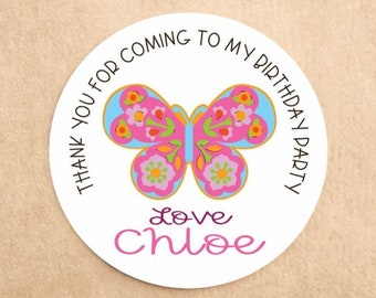 May include: A round white sticker with a colorful butterfly design. The butterfly has pink, blue, yellow, and green details. Text around the edge reads "THANK YOU FOR COMING TO MY BIRTHDAY PARTY." Below the butterfly is the name "Chloe" in pink script.
