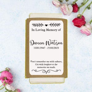 May include: A white card with a gold border and a black floral design. The card reads "In Loving Memory of Doreen Watson 13/01/1947 - 25/03/2023 Don't remember me with sadness, Cry with laughter at the memories we made."