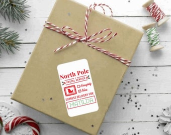 May include: White gift tag with red and green accents. It says "North Pole Postal Service" and has a checkbox for "Naughty" and "Nice". It says "Express Delivery for: MATILDA".