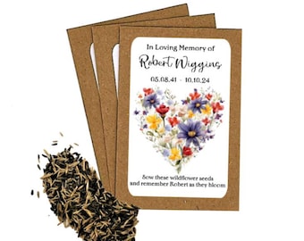 May include: A collection of wildflower seed packets with a heart-shaped floral design. The packets are brown with a white label that reads "In Loving Memory of Robert Wiggins" and includes dates. A pile of seeds is next to the packets.
