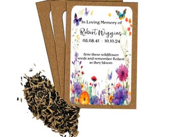 May include: A packet of wildflower seeds with a floral design and the text "In Loving Memory of Robert Wigging 05.08.41 - 10.10.24". The packet is surrounded by brown seed packets and a pile of seeds.