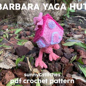 May include: A pink and white crocheted house with a bow on top, standing on a bed of small rocks and green leaves. The text "sunnyGstitches pdf crochet pattern" is at the bottom of the image.