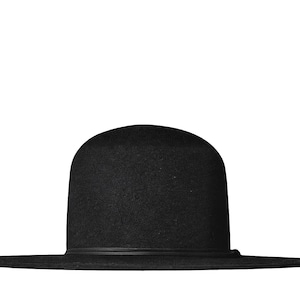 Può includere: Un cappello nero a tinta unita con una corona arrotondata e una tesa larga e piatta. Il cappello presenta un sottile nastro nero abbinato che circonda la base della corona, offrendo un aspetto pulito e uniforme all'intera struttura.