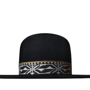 Może przedstawiać: Czarny kapelusz z szerokim rondem i zaokrągloną koroną. Kapelusz posiada ozdobną opaskę z geometrycznym wzorem w kolorze białym, czarnym i złotym. To stylowy dodatek.