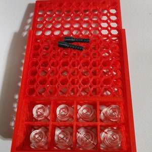 May include: Red plastic shot glass holder with eight clear shot glasses and two black rubber stoppers.